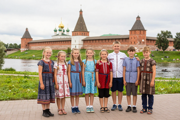 Children on excursion in ancient Russian city, Suzdal kremlin background, cheerful group